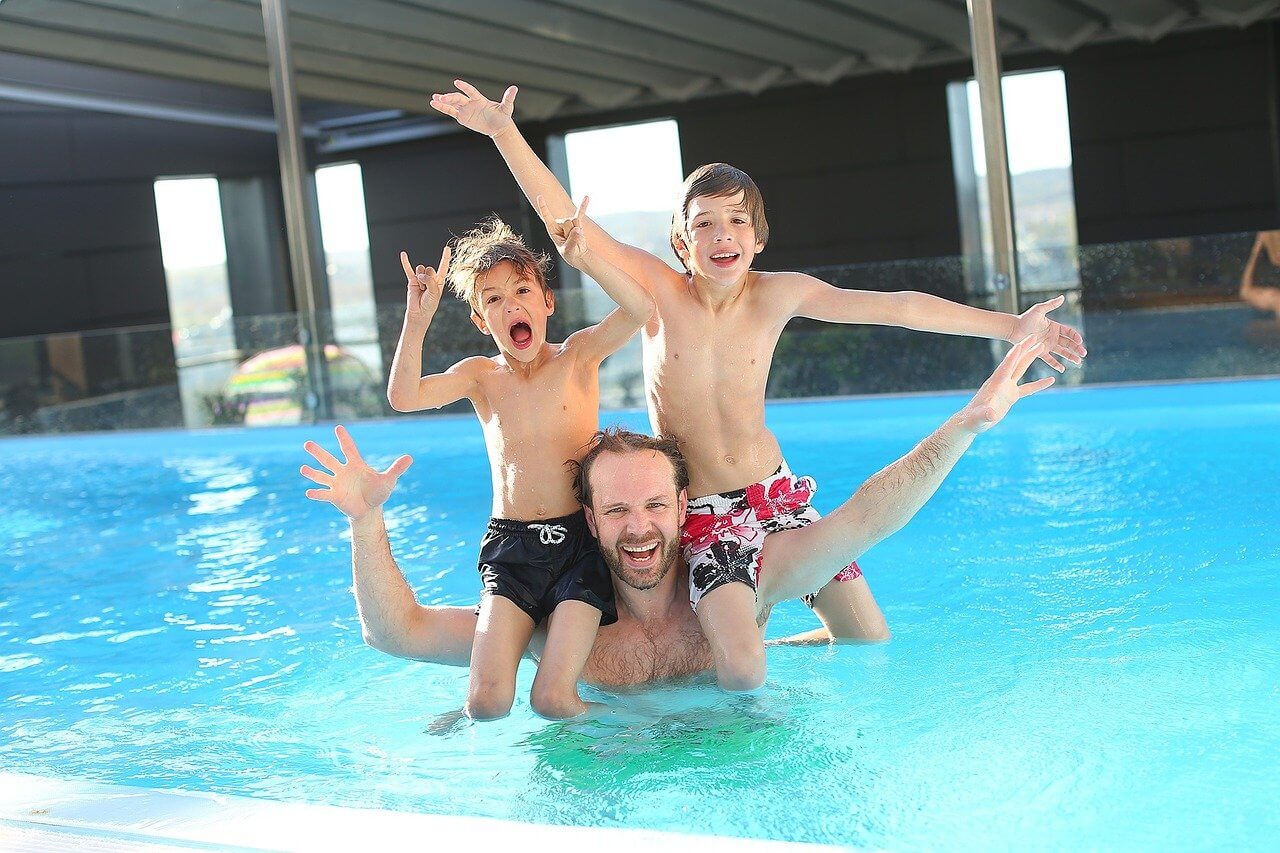 Un padre y sus dos hijos jugando en una piscina